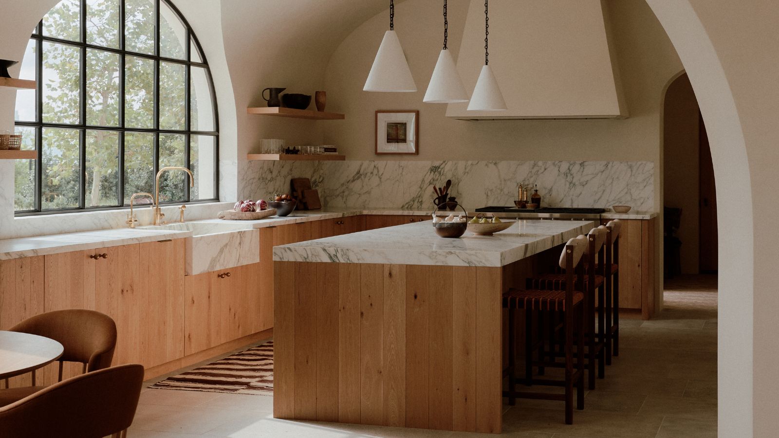 A wooden kitchen with plaster walls and marble countertops