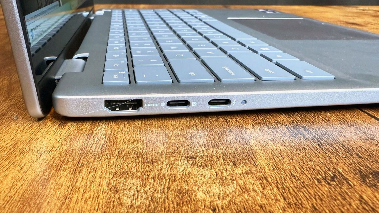 Close up of the left-side port array on the Dell 14 Plus 2-in-1 (Intel) laptop on a wooden desk, against a black backdrop.