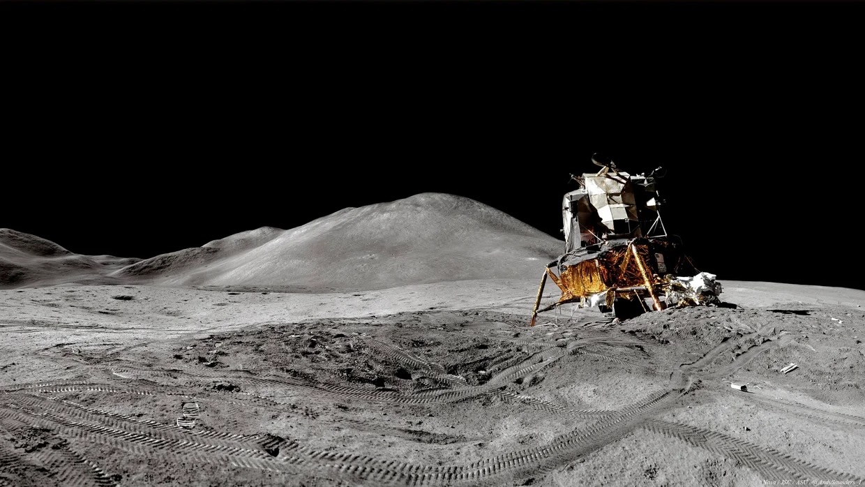 foto de uma espaçonave branca e dourada inclinada na borda de uma pequena cratera na lua
