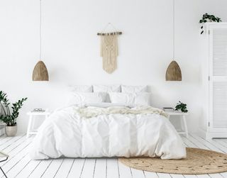 A stark, white Scandi-style bedroom with a bed, dresser, and rug and a few plants