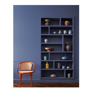 blue bookcase with books and objects in front of wall in the same blue