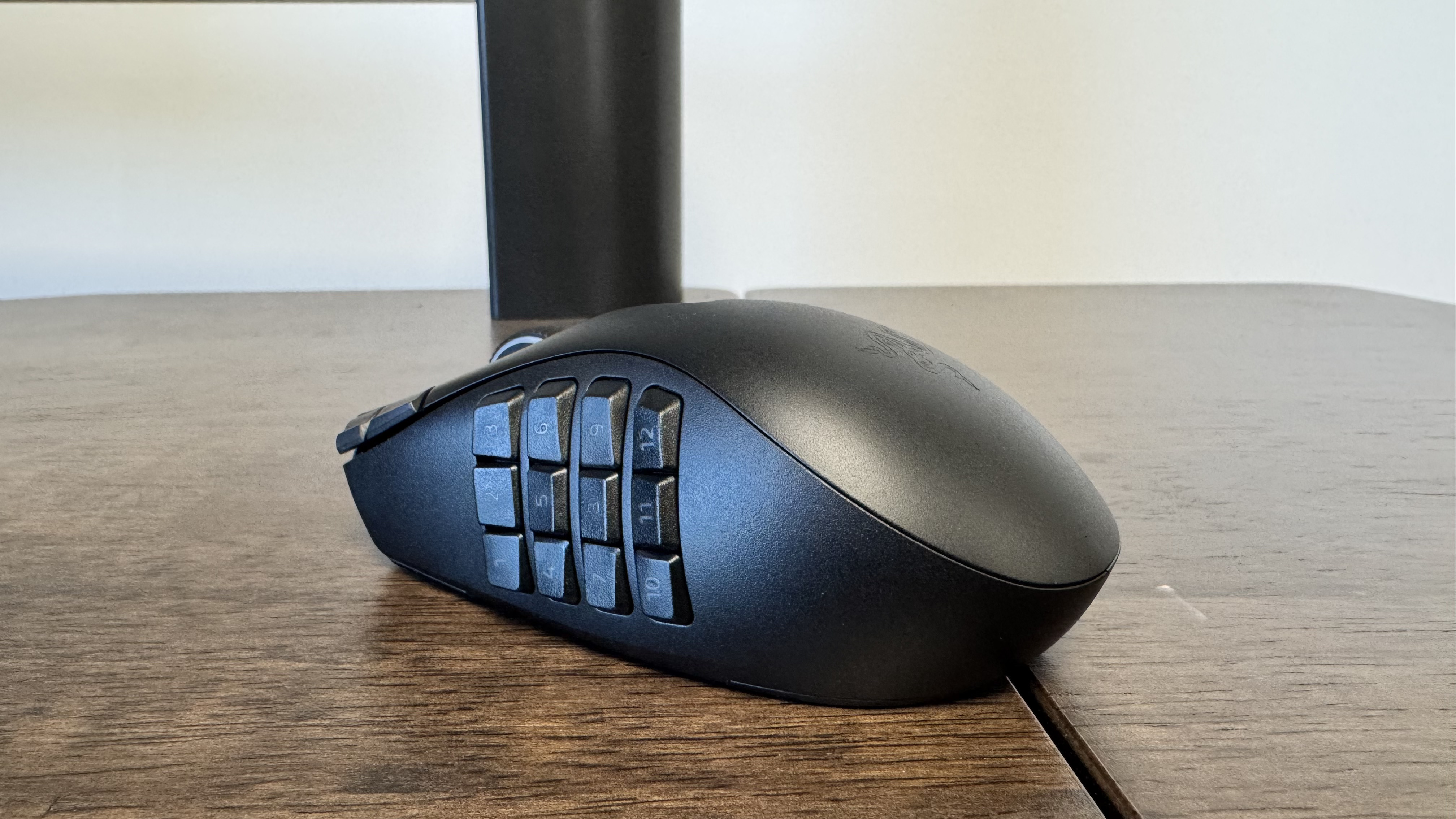 The Razer Naga V3 Pro on a wooden table from the back left