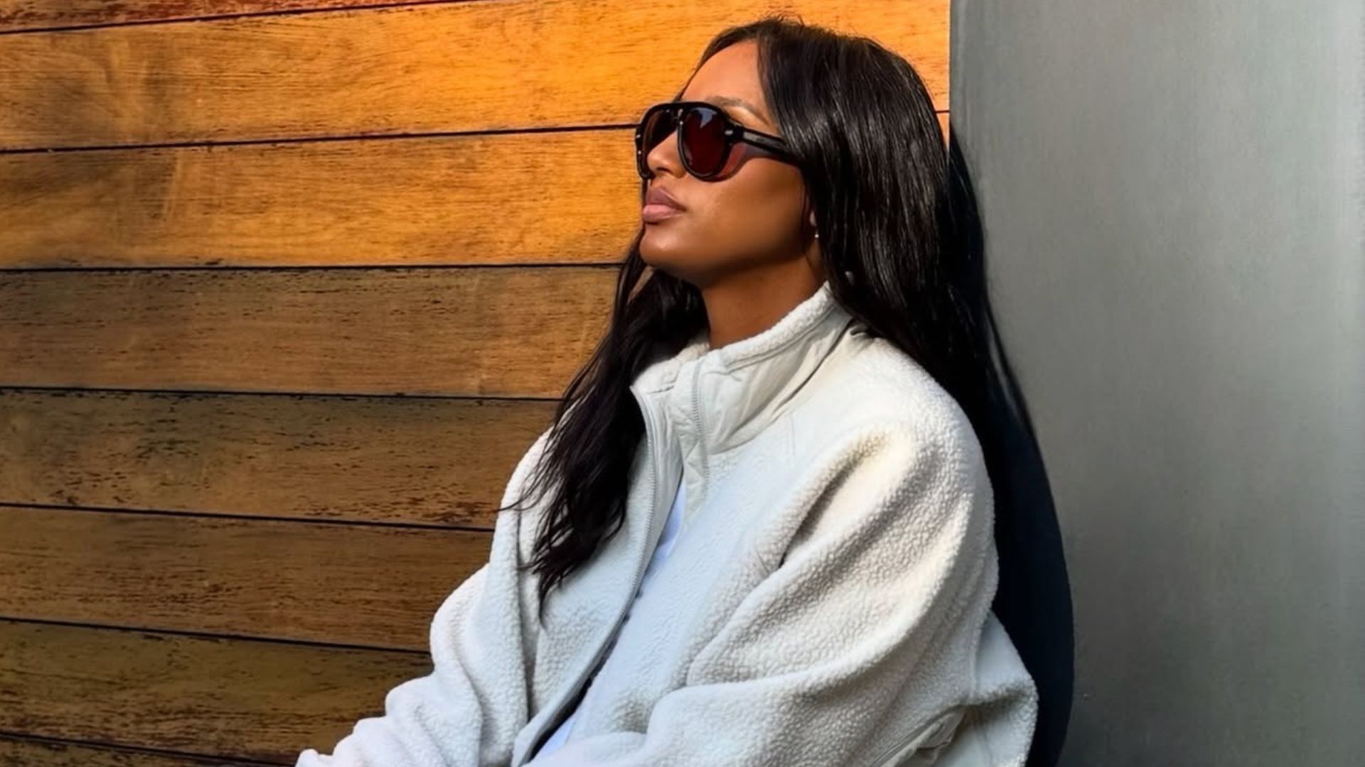 Influencer @jastookes crouches down wearing navy leggings with white New Balance trainers, a white fleece and a brown Hermes bag.