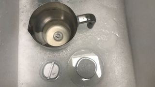 smeg milk frother in parts in a sink