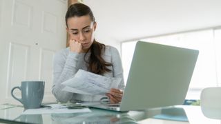 worried woman sitting at table with a laptop looking at her energy bills