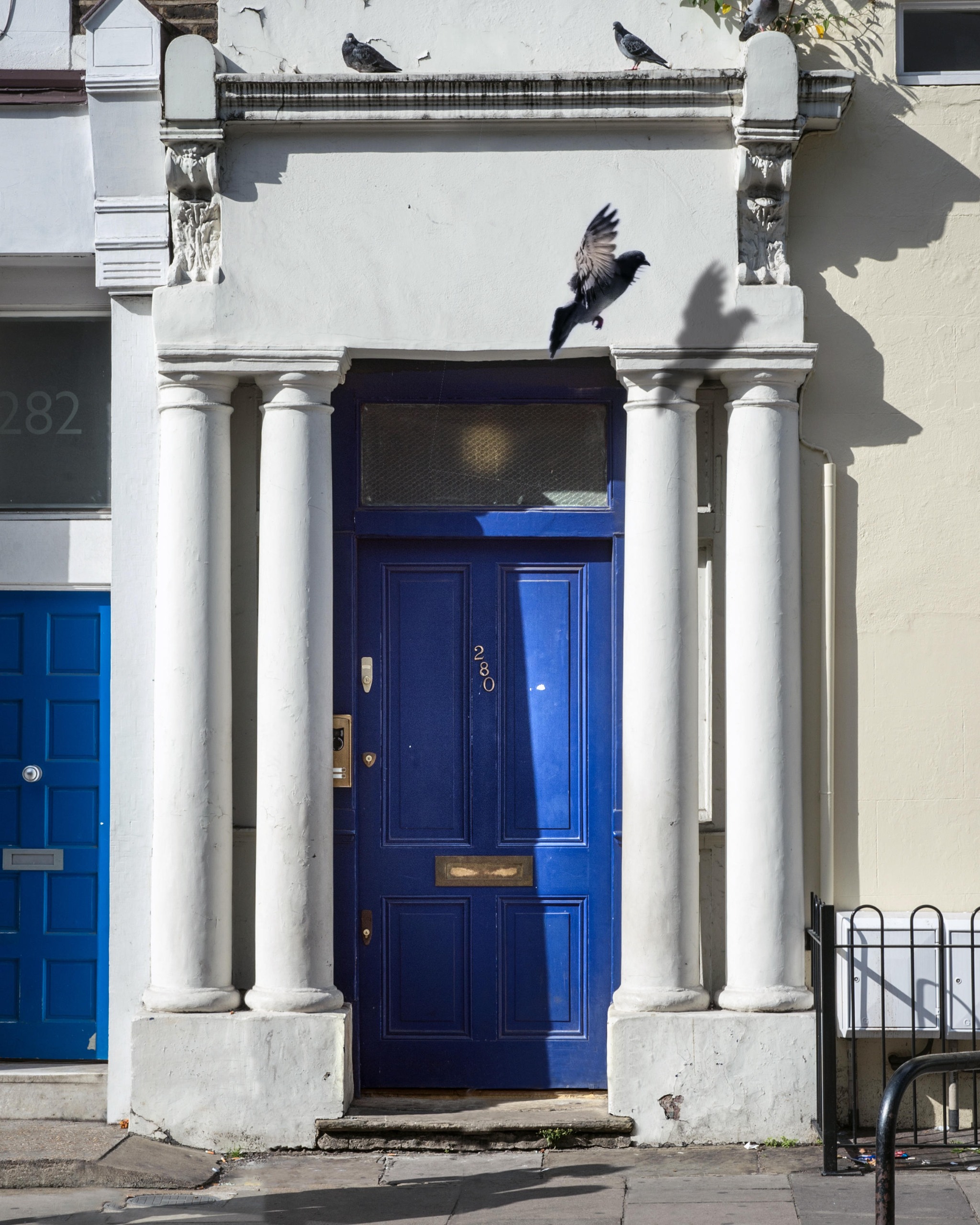Cobalt blue front door with two slim white columns either side