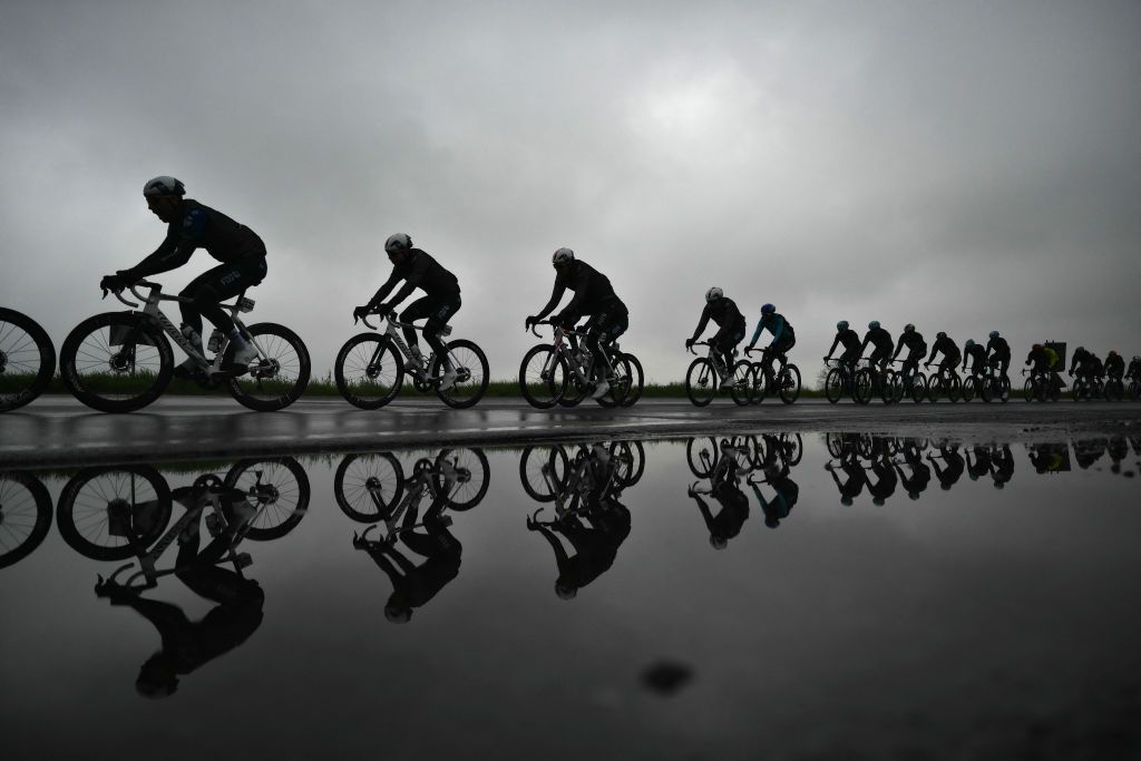 Rider reflect in a puddle during the Milan - Sanremo one-day classic cycling race, near Milan, on March 22, 2025. (Photo by Marco BERTORELLO / AFP)