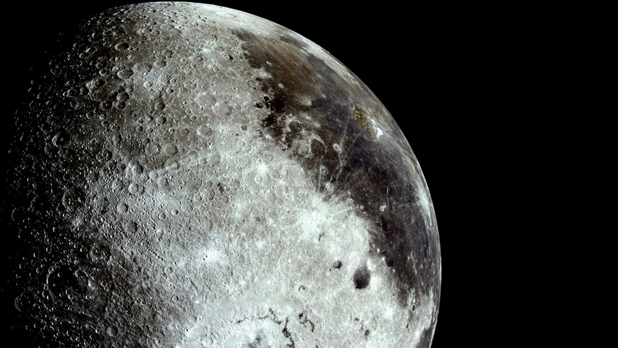 A close up of the moon's surface, showing several glowing craters and dark areas.