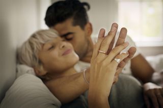sexual positions and emotional investment - Affectionate young man kissing woman while holding hand in bedroom