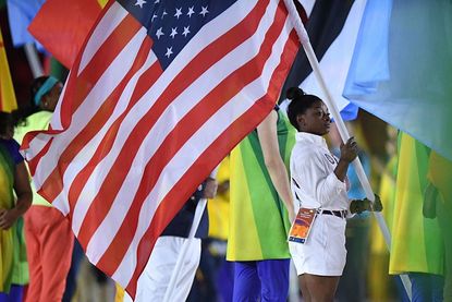 Simone Biles carries the American flag during the closing ceremony.