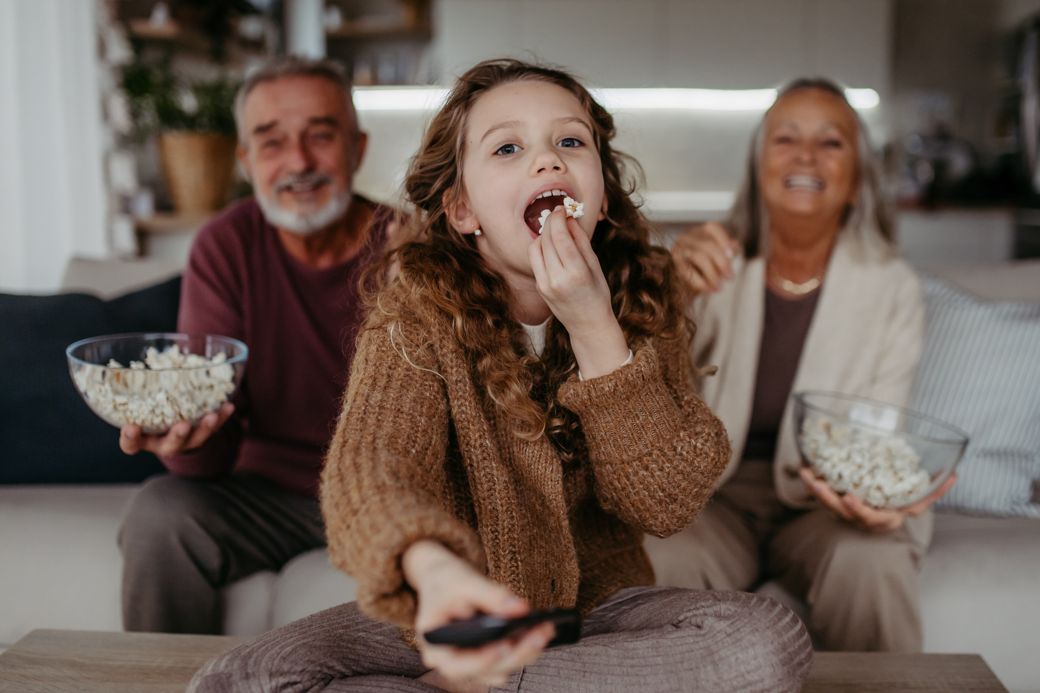 Grandparents watching TV with their granddaughter.