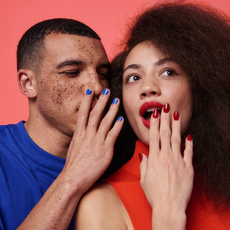 Man whispering to woman, both wearing nail polish, pink ground