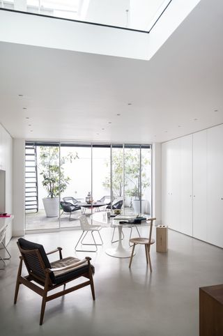 A minimalist living room with glass table, assorted chairs