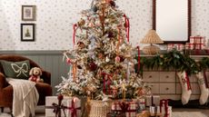Christmas tree adorned with bows featured in a festive living room with accent chairs and gift-wrapped presents