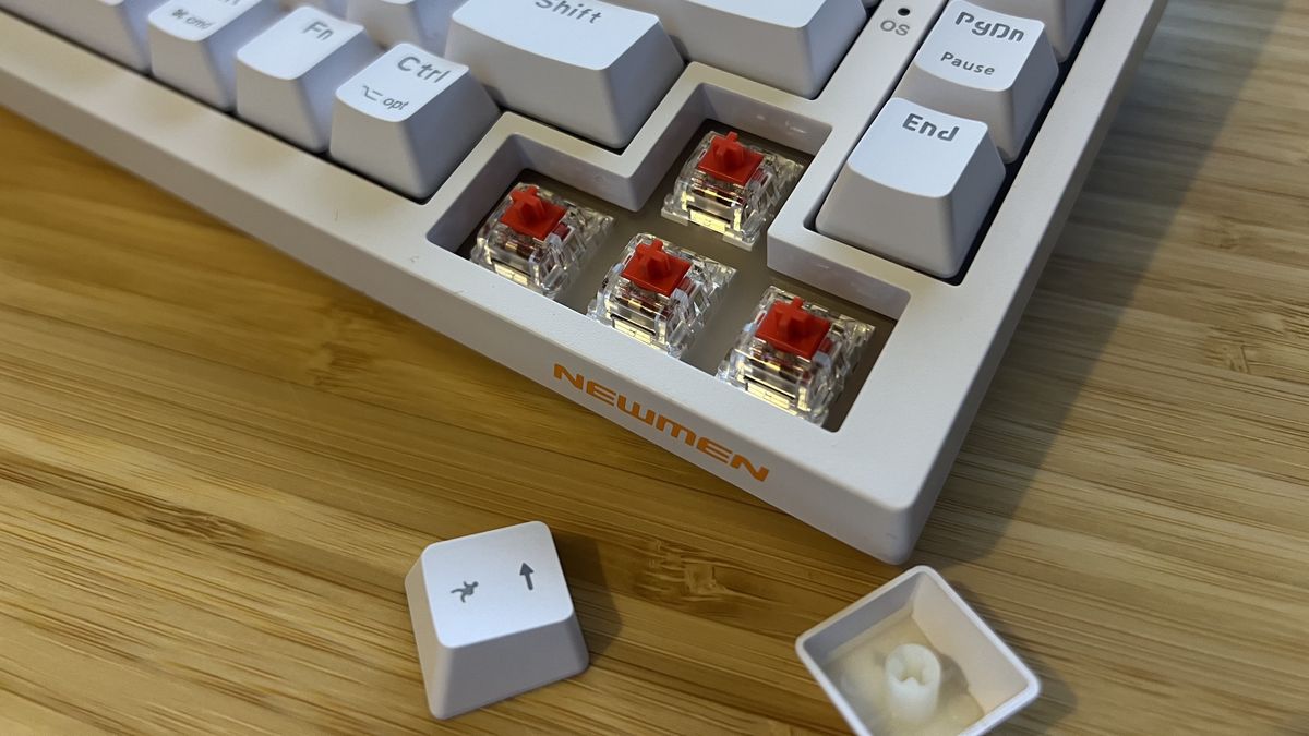 Close up on arrow buttons of Newmen GM326 gaming keyboard with caps removed to show switches