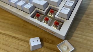 Close up on arrow buttons of Newmen GM326 gaming keyboard with caps removed to show switches