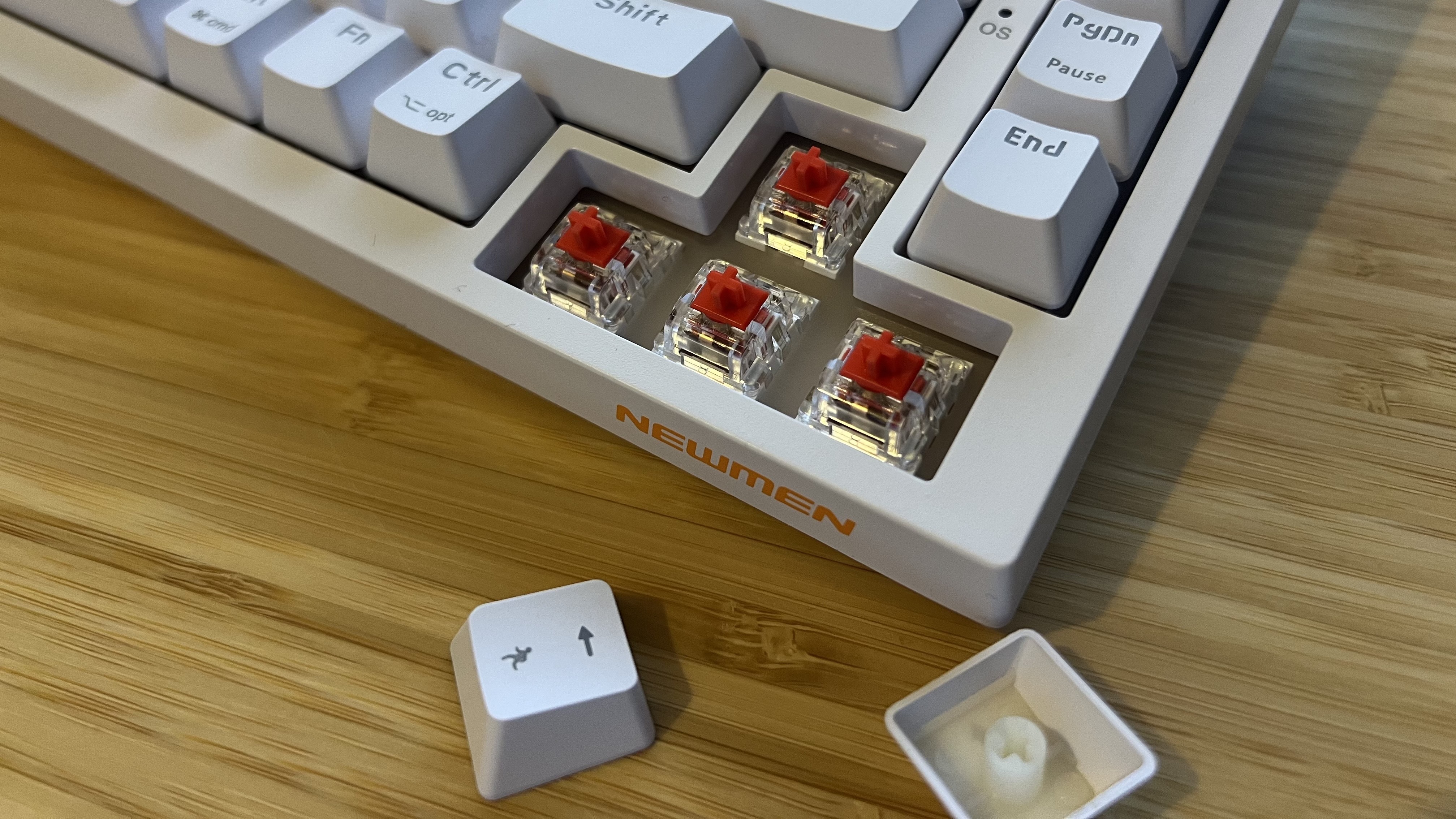 Close up on arrow buttons of Newmen GM326 gaming keyboard with caps removed to show switches