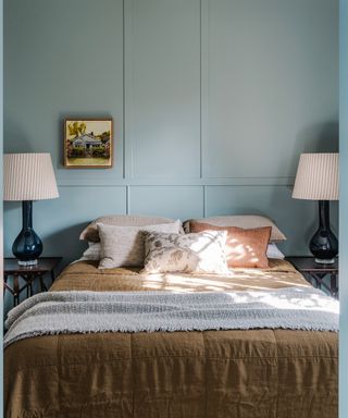 bedroom with duck egg panelled walls and ochre throw