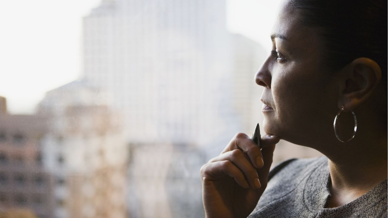 An executive thoughtfully looks out her office window.