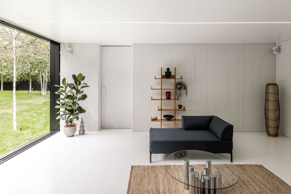 A white living room with floor to ceiling window and recessed lights on the ceiling