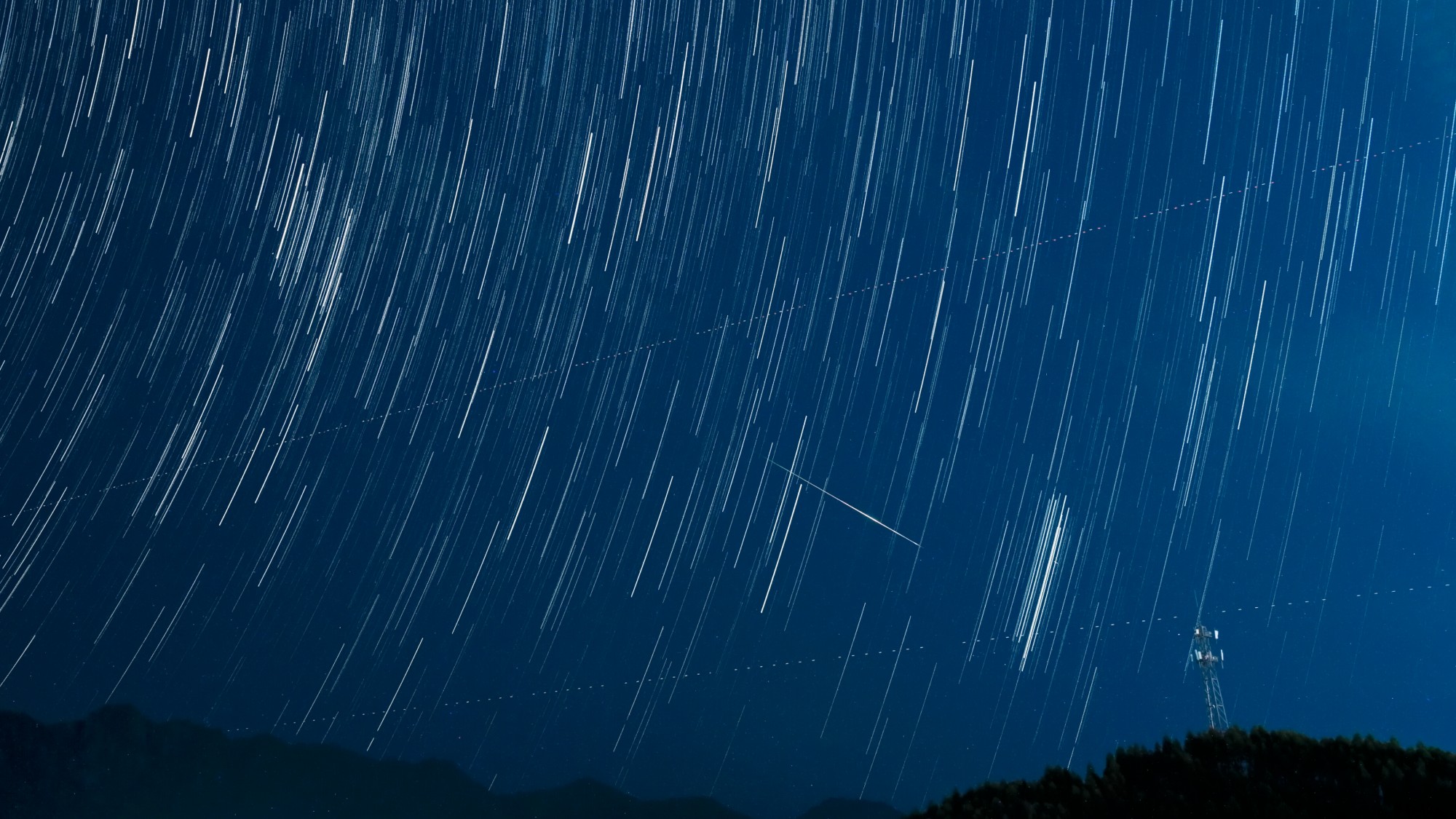 a streak of light crosses through the night sky