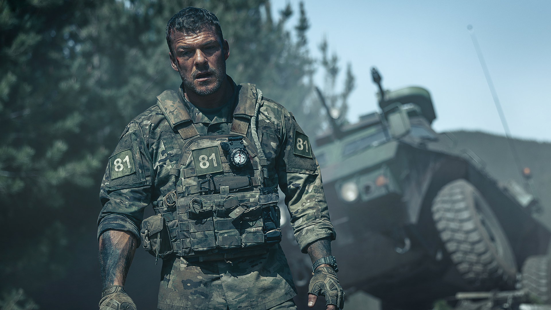 Alan Ritchson's US marine standing next to a ruined vehicle in Netflix's War Machine movie