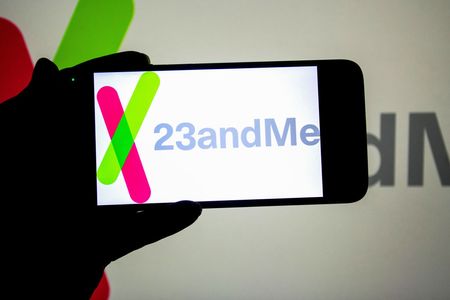 In this photo illustration, a 23andMe logo seen displayed on a smartphone and in the background.