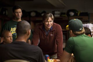 brad pitt smiles while talking to a team of baseball players in moneyball