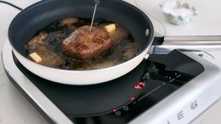 Steak cooking on a Smeg portable induction cooktop