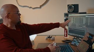 Infinity Ward studio audio director Stephen Miller sits at a desk with a computer. Audio mixing software is displayed on the screen, and Miller is discussing the audio tech behind Modern Warfare 4.