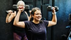 Woman doing overhead press as part of the 2-2-2 workout in the gym