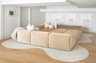 a white room with a large pit sofa and an irregular rug