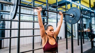 Woman performs the overhead press with a barbell