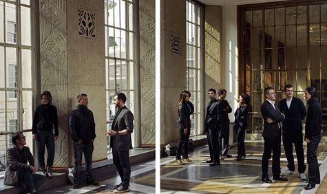 men and women all in black formal workwear standing in a large room talking with each other