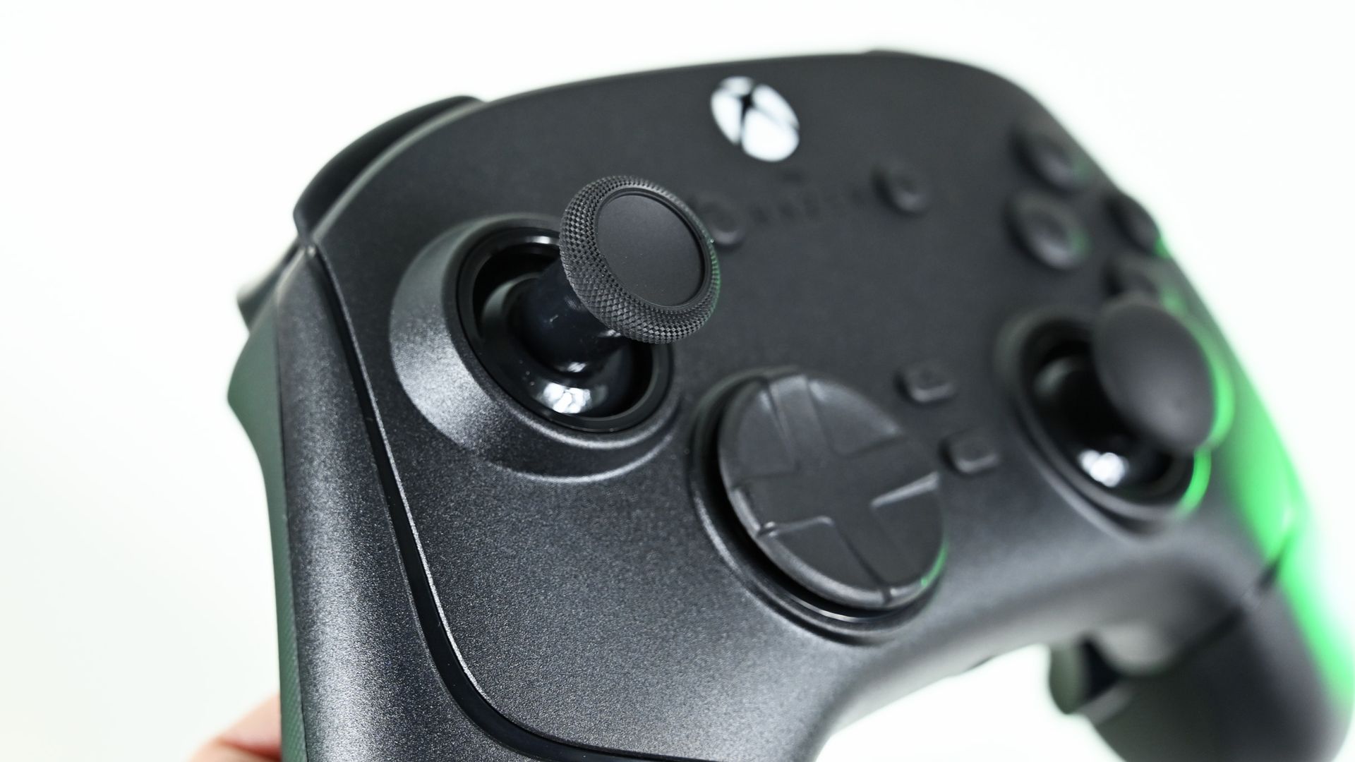 Close-up of the controller's textured left analog thumbstick, hybrid directional pad, and glowing Xbox guide button.