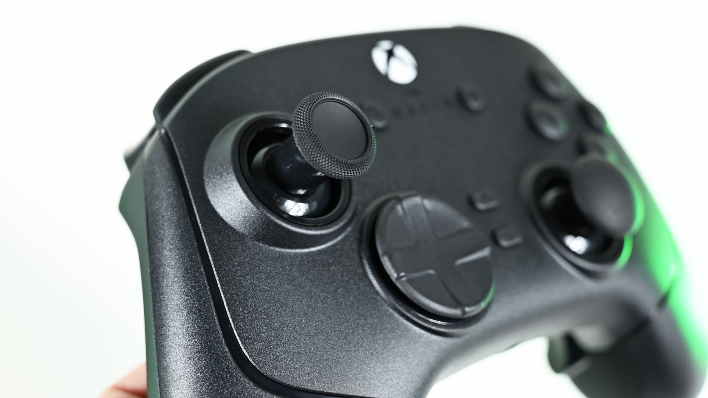 Close-up of the controller's textured left analog thumbstick, hybrid directional pad, and glowing Xbox guide button.