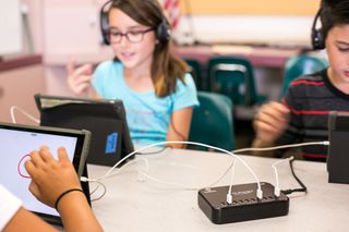 Kids using headphones, tablets and ThinkWrite charging hub in classroom