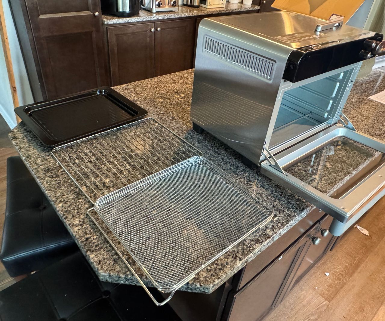 The Typhur Sync Air Fryer Oven on a granite work top beside the trays