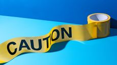 A roll of caution tape against a blue background.