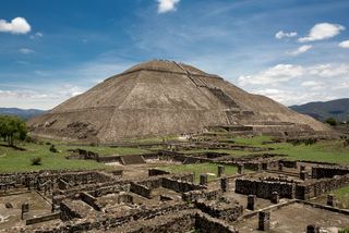 The Pyramid of the Sun in the ancient city of Teotihuacan with ruin walls in the foreground.