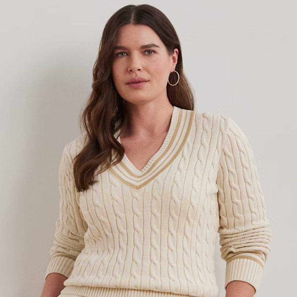 Brunette young woman in her thirties wearing white cable-knit cricket sweater by Ralph Lauren.