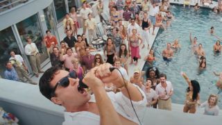 Leonardo DiCaprio works the mic in front of a crowded party in The Wolf of Wall Street.