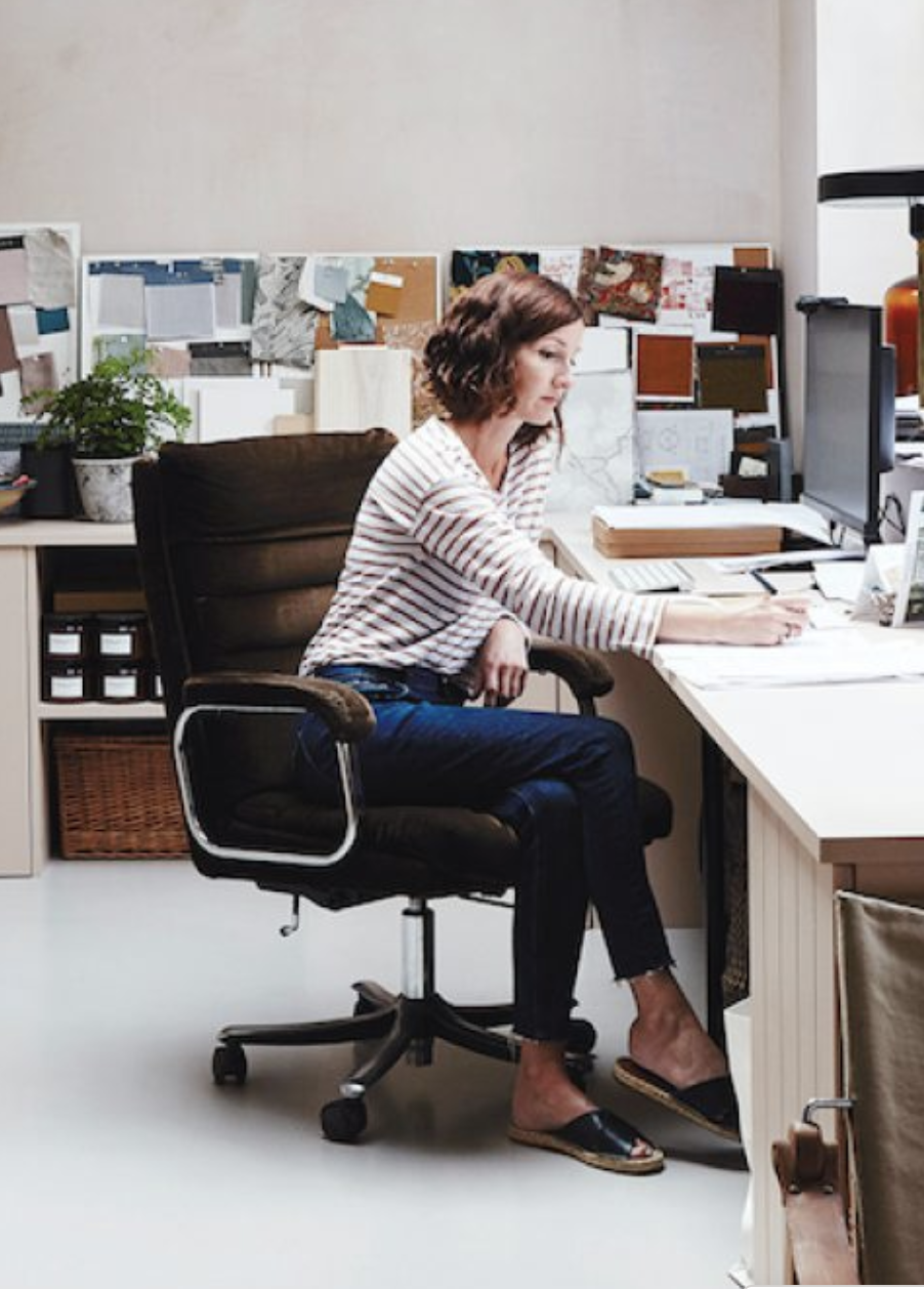 woman wearing striped top and jeans sitting at a desk