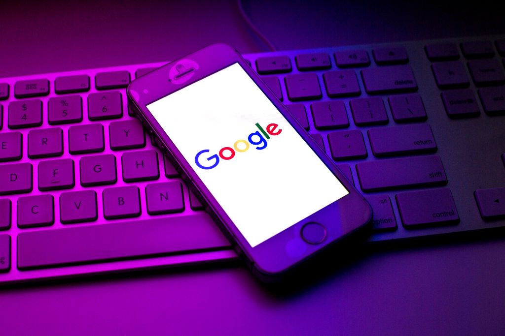 The Google logo displayed on a smartphone resting on a keyboard