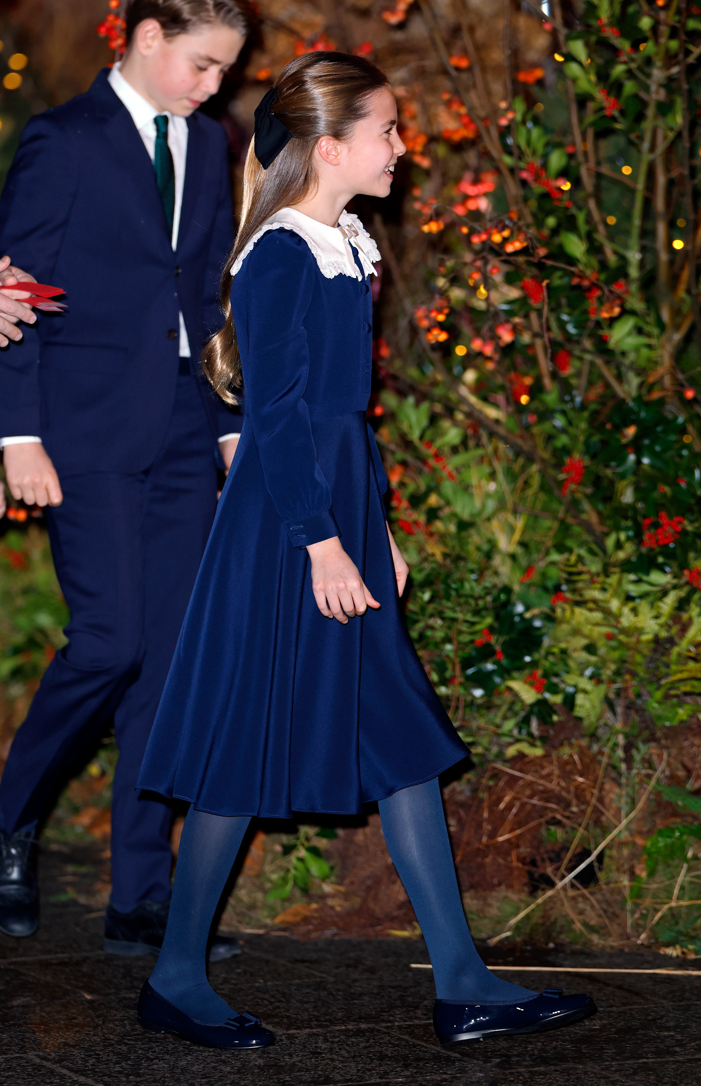 Princess Charlotte wearing a navy dress walking with Prince George