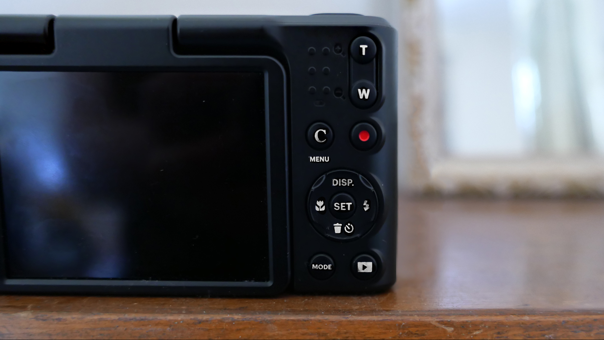 Close-up view of the Kodak Pixpro C1's digital camera's back panel featuring buttons and a blank display screen on a wooden surface