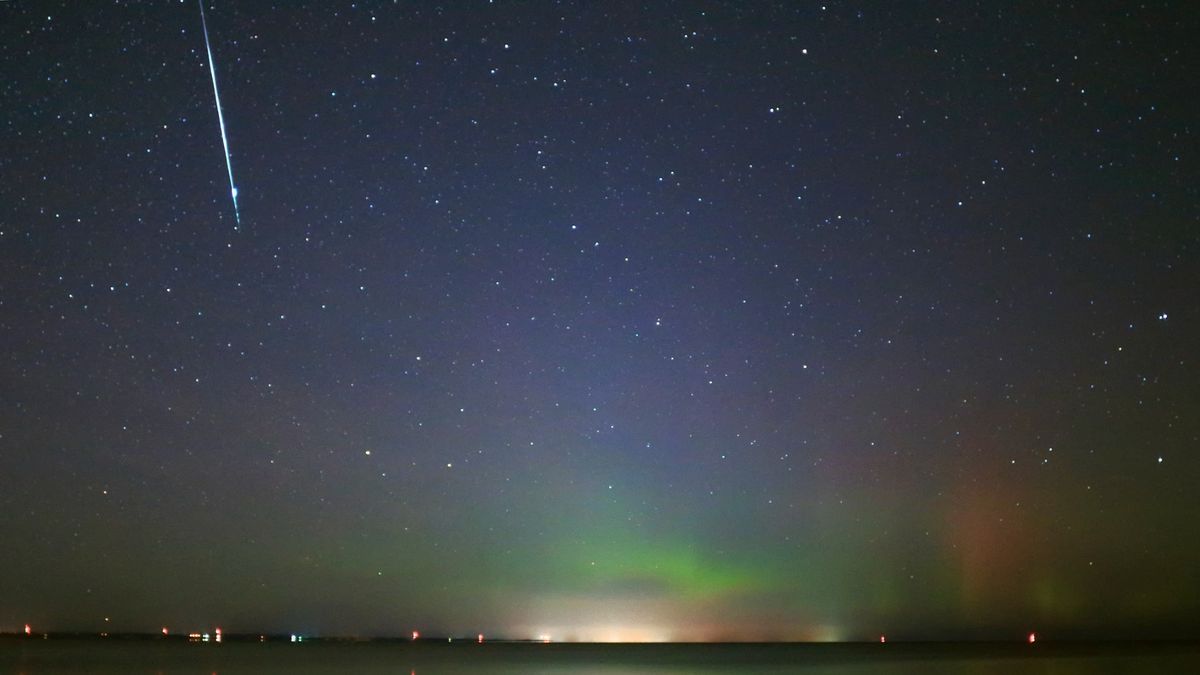 A bright Taurid meteor descends across a sky featuring a glowing aurora over Lake Simcoe on Nov. 9, 2015