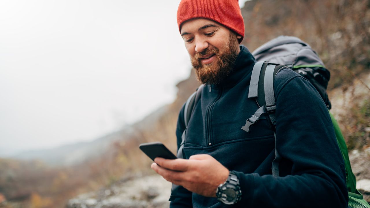 A man on a hike looking at his phone