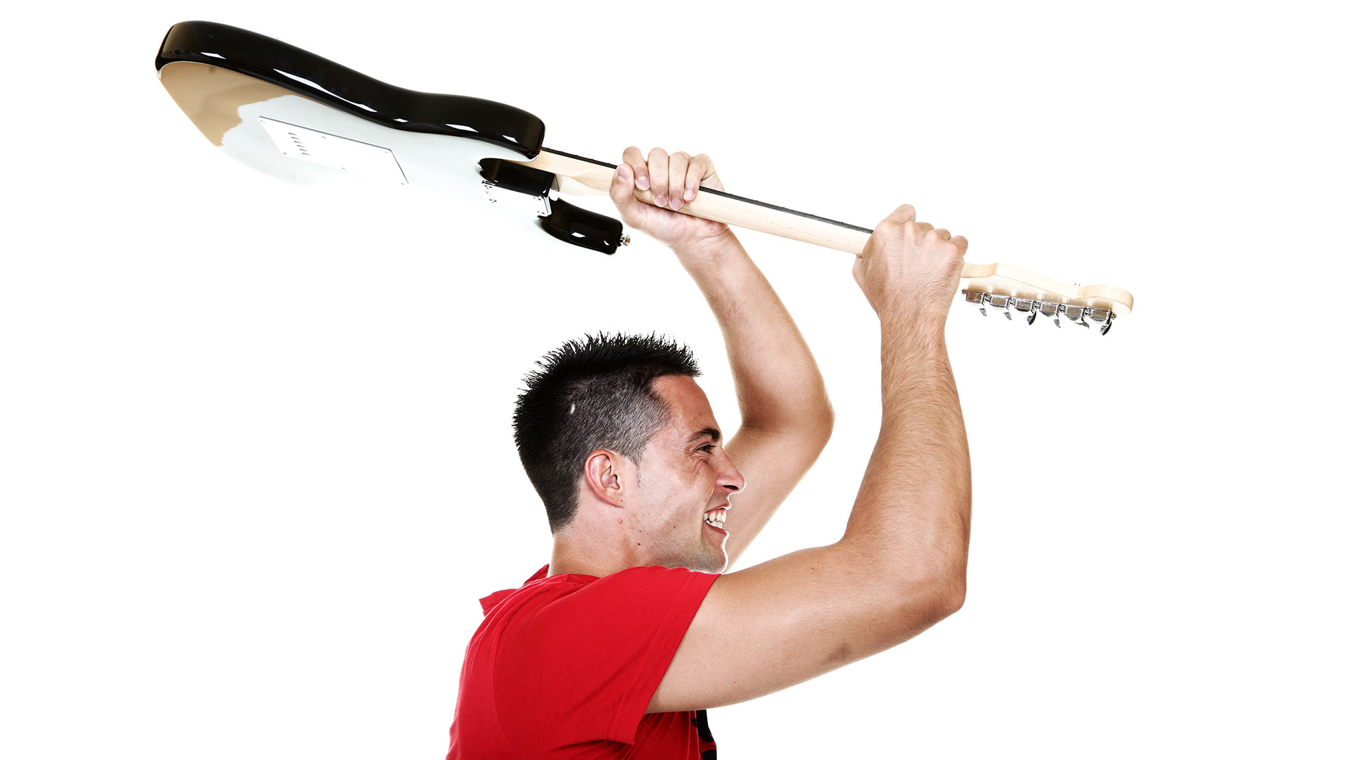 A man in a red shirt moves to smash his Stratocaster style guitar