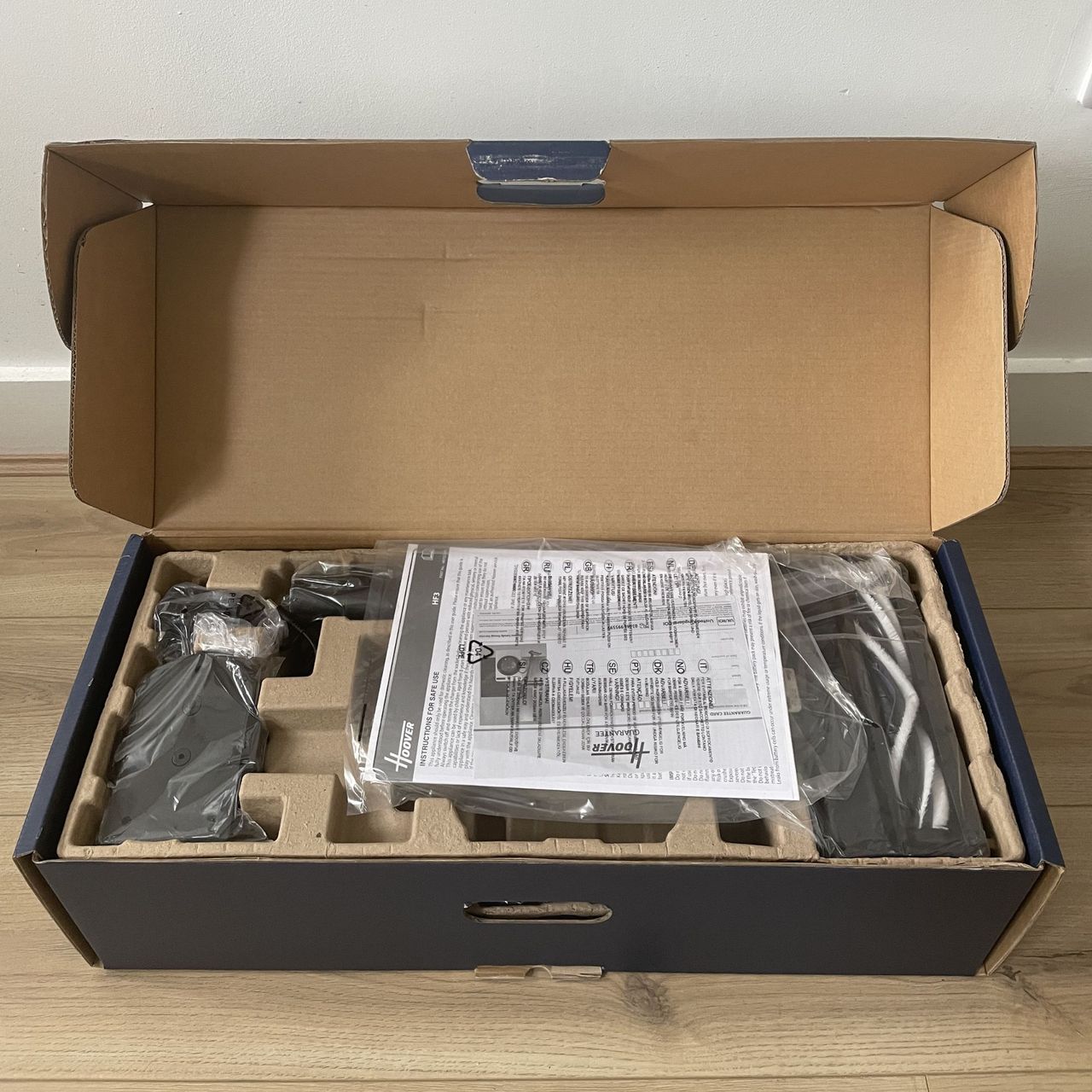 Open box of the Hoover HF3 Pet DynamicClean Cordless Vacuum, with the lid open and showing the components inside